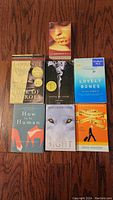 Top-down image showing seven fiction books arranged in two rows on a wooden surface