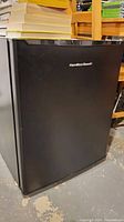 Closed view of the black Hamilton Beach mini fridge showing the front door and brand logo.