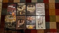 Photo showing 8 DVD cases laid out on a patterned carpet: A Bridge Too Far, Jarhead, The Longest Day, The Nazis, The Pacific, Pearl Harbour, Flyboys, and The Thin Red Line.