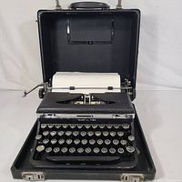 Full view of the 1939 Royal 'O' Deluxe typewriter inside its open carrying case, showing paper loaded and keys visible.
