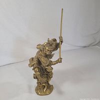 Full view of brass Monkey King statue in a dynamic pose with staff, showing cloud base and overall silhouette.