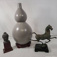Full view of all three items: double gourd vase, flying horse bronze sculpture, and Buddha bust statue