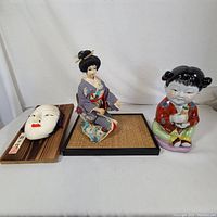 Front view of Noh mask, Japanese doll and Chinese girl figure on plain background