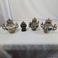 Front view showing three silver-inlaid ceramic burners with dragon handles and central green cloisonné jar on stand