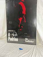 Front view of the Il Padrino The Godfather vintage poster showing red silhouette and white text on black background, framed.