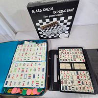 Open wooden box showing large mahjong tiles neatly organized, with poker chips underneath one set of tiles.