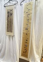 Two scroll paintings hanging side by side against white backdrop