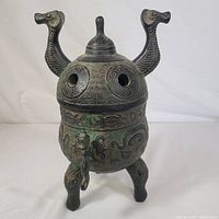 Front view of assembled incense burner showing lid, dragon head spouts and tripod base
