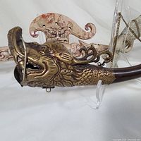 Close-up of brass dragon head attached to wooden handle of libation spoon