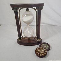 Front view of wooden hourglass with hand blown glass and two round wooden Chinese zodiac compass swivel boxes