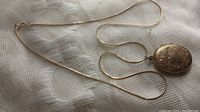 Chain and locket laid out together on fabric background