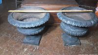 Two urns side by side with a measuring rod across tops