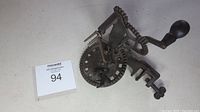 Full view of antique apple peeler showing hand crank, gears, and clamp attachment.