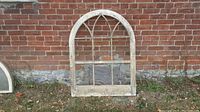 Front view of antique arched wooden window frame against a brick wall showing full size and structure.