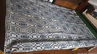 Full view of coverlet laid flat showing overall geometric pattern and fringe edges.