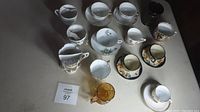 Top-down view of 11 antique and vintage cups and saucers arranged on a table.