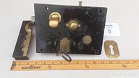 Front face of iron lock body with attached brass knob, key in lock