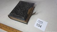 Closed antique photo album with patterned black cover and metal clasp