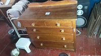 Front view of the antique pine dresser showing four drawers with round wooden knobs, a raised backsplash on top, and some surface scratches and wear.
