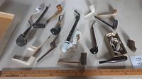Wide view of various antique pipes arranged on table for scale comparison.