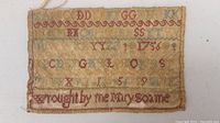 Front view of entire sampler showing stitched alphabet rows and inscription
