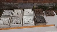 Nine hand carved wooden architectural elements arranged on table with ruler for size reference, mixed white painted and natural wood tones