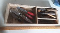 Wood chisels with wood and red handles in wooden box with two compartments and ruler in front