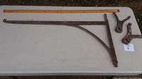 Full crane arm laid flat on table alongside two support brackets and a measuring ruler