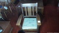 Front view of the solid oak armchair showing wide armrests and upholstered seat cushion.