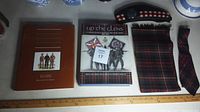 Photo shows all lot items laid out including the two books, the Glengarry Fencibles cap with badge, and the tartan scarf and tie.