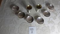 Two silver goblets and six dipping bowls arranged on tablecloth