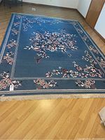 Full view of the blue floral patterned area rug laid out on wooden floor, showing the size and pattern details.