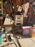 General view of garage corner with car jacks, stands, cables, boxes, shelving unit and other tools