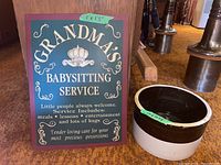 Photo of metal decorative sign reading 'Grandma's Babysitting Service' with detailed text and design.