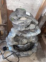 Full view of multi-tiered outdoor composite garden fountain with pump and electrical cord, showing stacked basin design in a weathered gray finish.