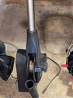 Outrigger fishing reel mounted on a metal pole with fishing line spool and black recessed casing, showing the line through a small hole.