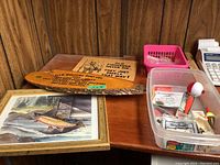 Overview photo showing the framed fish print, two wooden signs, and plastic container of fishing lures on a wooden corner table.