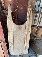 Top-down view of vintage wooden sled showing wooden surface and rope attached to metal hook.