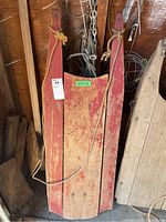 Top view of the vintage wooden sled with red paint and visible wear, rope attached to front.