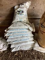 Stack of nine full bags and one partial bag of Black Earth Top Soil in a wooden shed.
