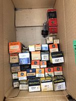 Photo showing multiple vintage vacuum tubes in original boxes, various brands and models.