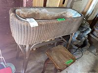 Wicker planter with metal liner on stand and small wood stool beside it in garage setting.
