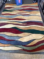 Full view of the rectangular area rug showing the multicolor abstract wave pattern across its surface.