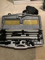 Opened hard plastic carrying case showing telescope tube, tripod, and accessories fitted inside the molded compartments.