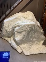 Full view of a large white blanket or duvet draped on the floor and staircase.