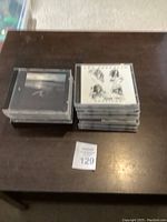 Two stacks of CDs on a wooden table; one stack has clear jewel cases with visible Led Zeppelin and Robert Plant album covers.