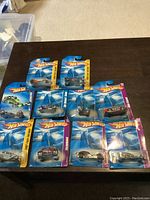 Photo showing all unopened Hot Wheels cars on a dark table, in original packaging, ten total.