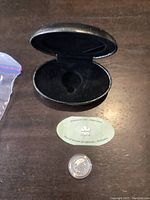 Open black hard shell coin case showing interior slots and surface.