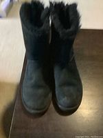 Front view of black suede UGG boots showing rounded toe and shearling lining.