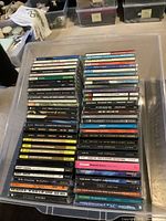 Photo of a large plastic container filled with 60 assorted CD jewel cases, mostly classic rock and blues albums